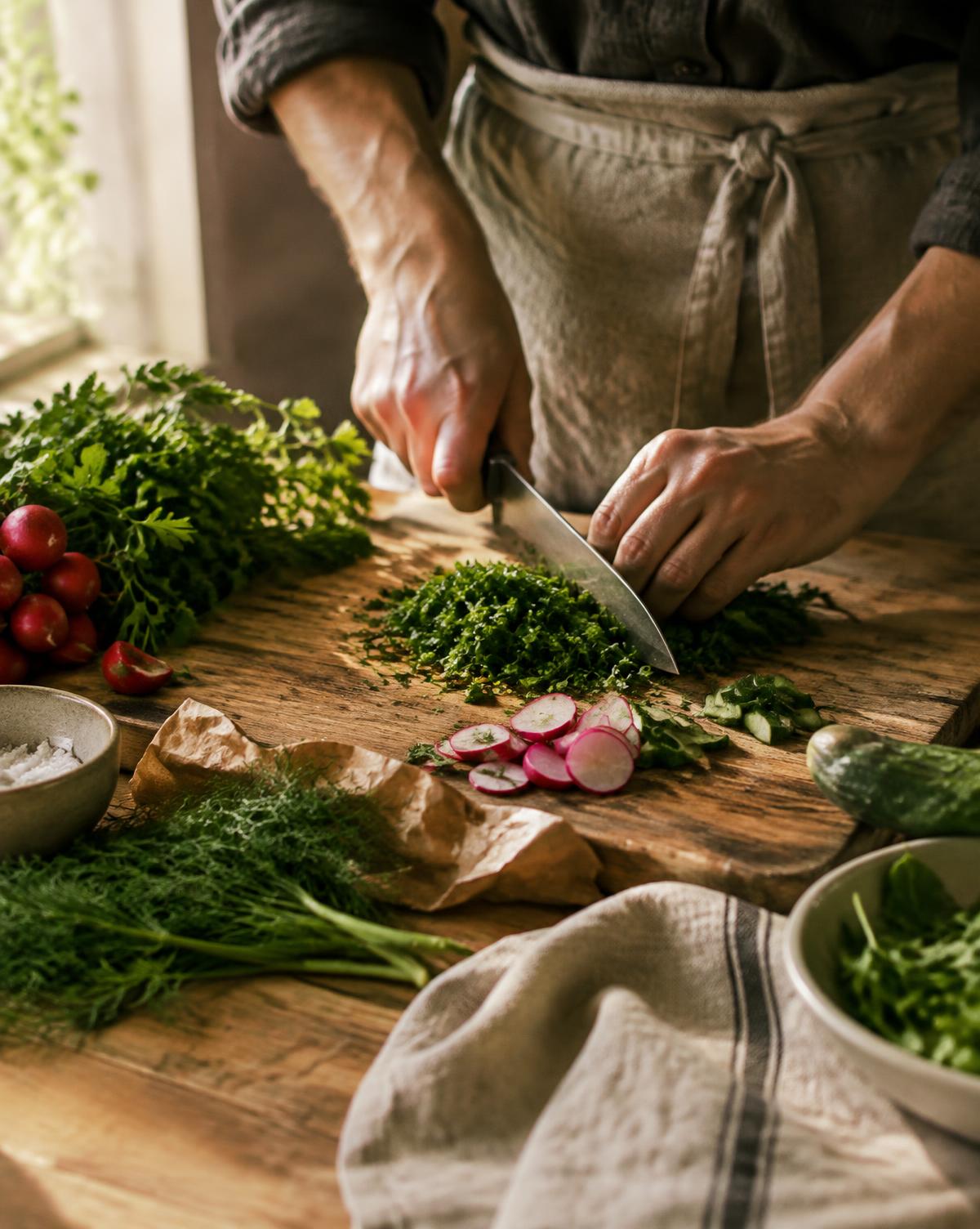 Mãos preparando ervas frescas sobre tábua de madeira
